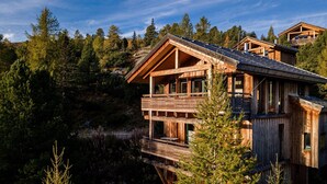 Une cabane en bois dotée d’un balcon, entourée d’une forêt dense.