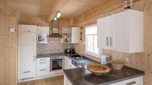 Une cuisine moderne avec des murs en bois, des meubles blancs, un pare-feu en carreaux et un plan de travail en marbre.