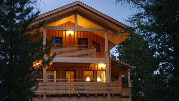 A two-story wooden cabin with a balcony, surrounded by trees. - Chalet in Alps near Ski Slopes and Sauna (Turracherhöhe)