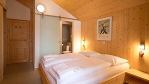 A wooden-paneled room with a bed, a bench, and a poster on the wall. - Chalet in Alps near Ski Slopes and Sauna (Turracherhöhe)
