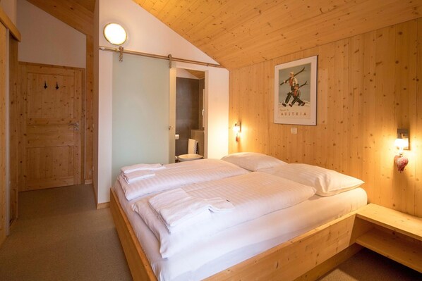A wooden-paneled room with a bed, a bench, and a poster on the wall. - Chalet in Alps near Ski Slopes and Sauna (Turracherhöhe)