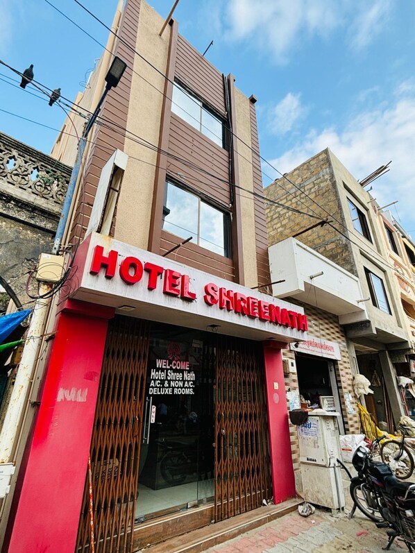 A hotel named "Hotel Shree Nath" with a red facade and a signboard. - Hotel Shreenath - Dwarka (Dwarka)