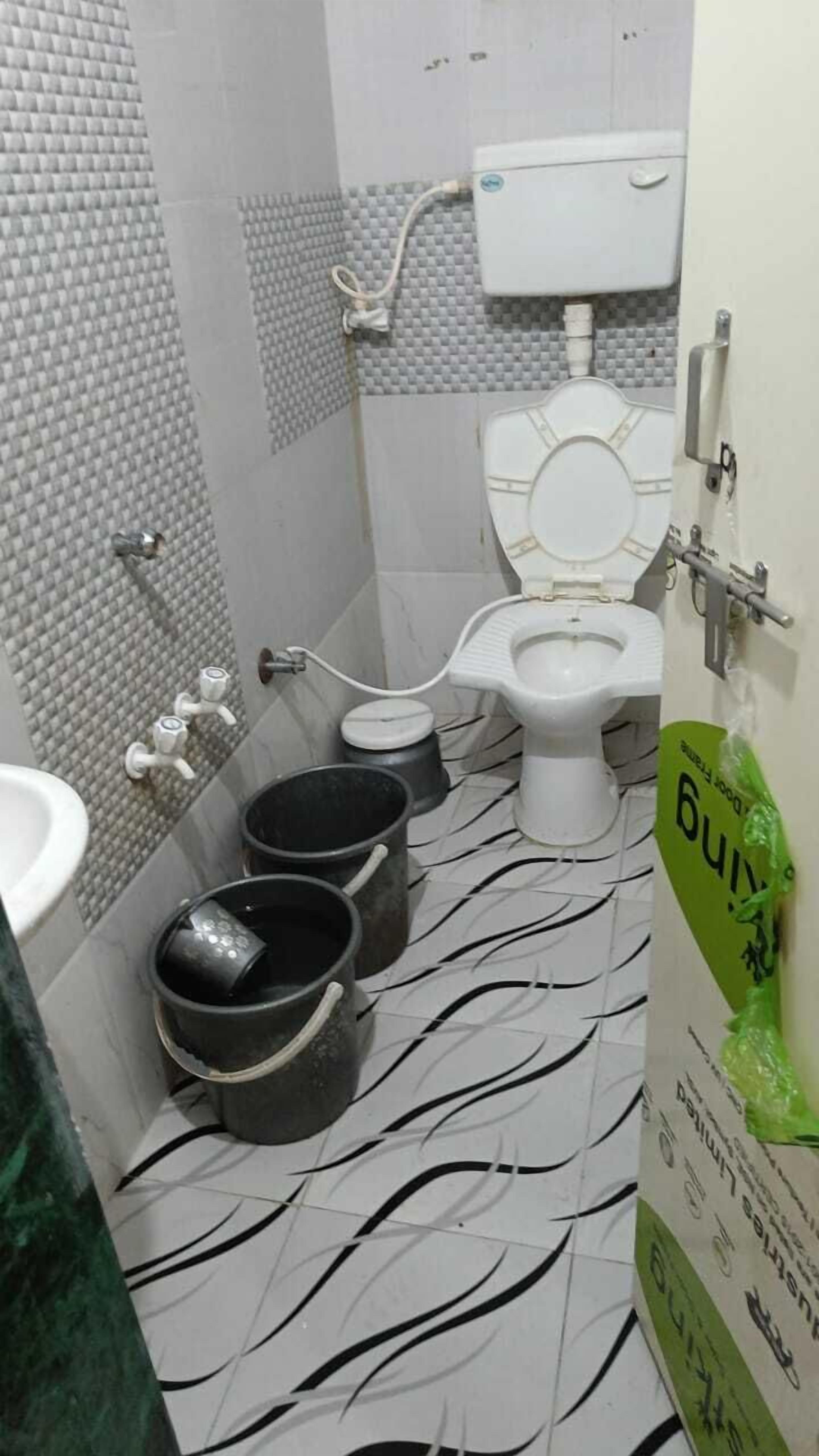 Un baño pequeño con inodoro, lavamanos y dos cubos.