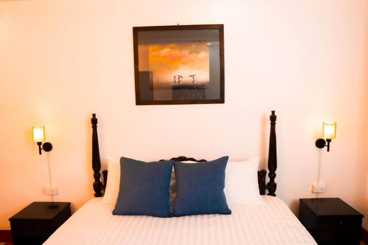 Een hotelkamer met een bed, twee nachtkastjes en een ingelijste foto aan de muur.