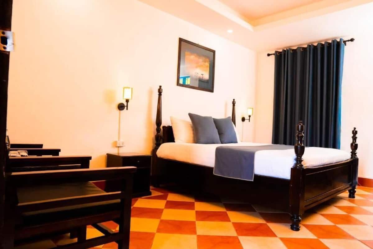 Een slaapkamer met een bed, nachtkastjes, een bureau en een stoel.
