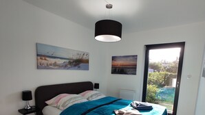 Une chambre à coucher moderne avec un grand lit, un ventilateur de plafond et des œuvres d’art accrochées aux murs.