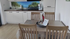 Une cuisine moderne avec des meubles blancs, une hotte noire et une machine à café. On y trouve une table à manger avec des chaises et un menu posé dessus.