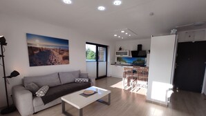 Un salon moderne comprenant un canapé, une table basse et un coin repas avec des chaises.