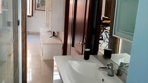 A modern bathroom with a large sink, mirror, and shower area.