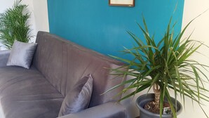 A living room with a blue wall, a gray sofa, and a coffee table with a framed picture.