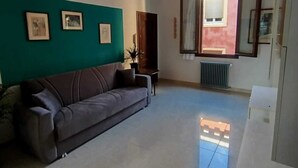 A living room with a sofa, a radiator, and a window with curtains.