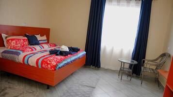 A hotel room with a wooden bed, a small round table, and a chair.
