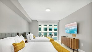 A hotel room with two beds, a large window, a TV, and a view of buildings. - Beautiful 1BR Apartment with Amenities (Miami)