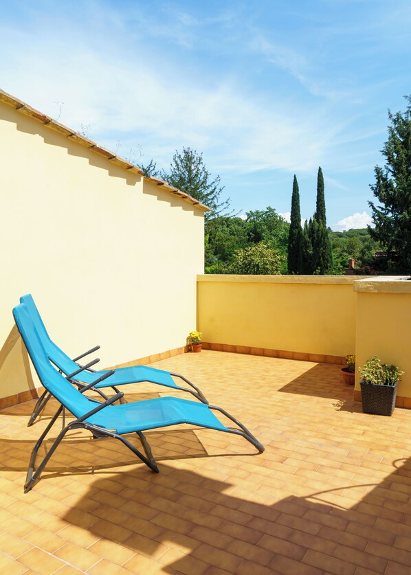 A rooftop terrace with two blue lounge chairs, a yellow wall, and potted plants. - Huge Villa with Swimming Pool in the heart of Rome (Roma)