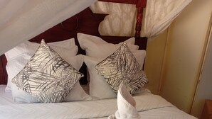A neatly made bed with a towel turban, patterned pillows, and a white quilted bedspread. - Lotus House Harare (Harare)