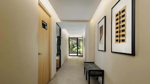 A hallway with a bench, framed artwork, and a door with a sign.