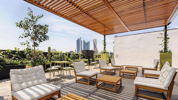 An outdoor seating area with wooden furniture and a view of the city skyline.