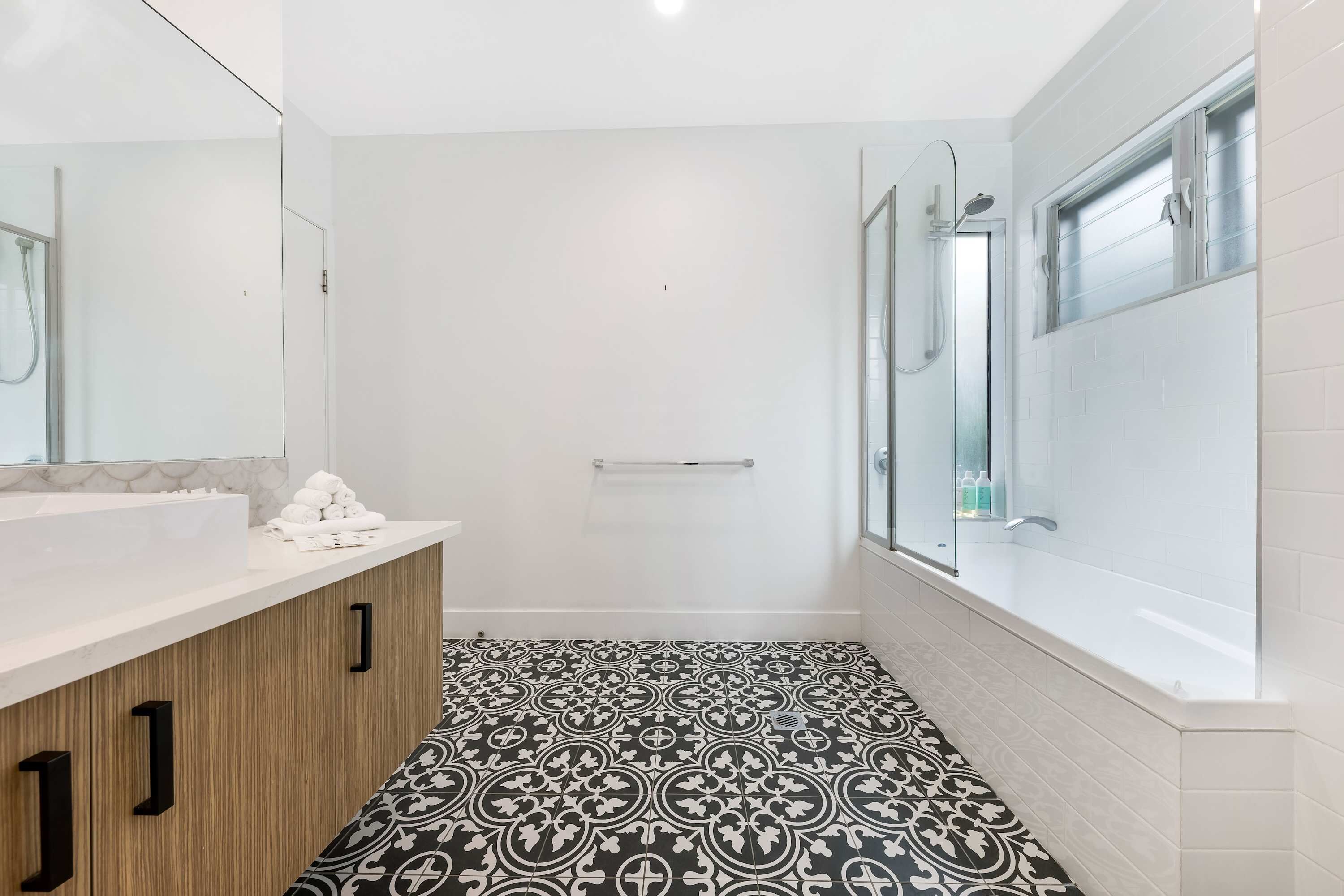 A modern bathroom with a large mirror, a sink, a shower, and a bathtub.