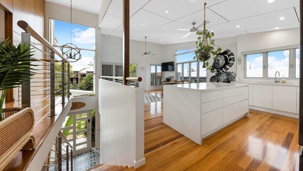 A spacious kitchen with a large island, wooden flooring, and a view of the outdoors.