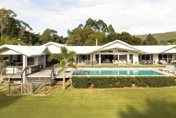 A modern hotel with a pool, outdoor seating, and a view of the surrounding greenery. - The Langville Estate in Kin Kin (Sunshine Coast Hinterland)