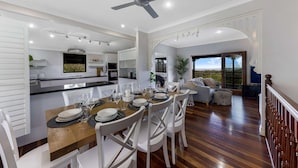 A modern kitchen with a dining area, a ceiling fan, and a view to the outside.