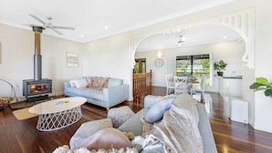 A living room with a sofa, a coffee table, a fireplace, and a dining area with chairs.