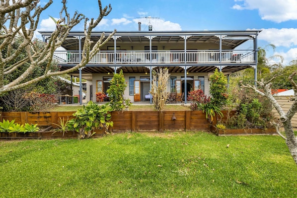 A two-story house with a balcony, a wooden fence, and a well-maintained garden.