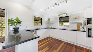 A modern kitchen with white cabinets, a black countertop, and a wooden floor.