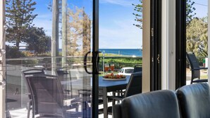 A dining area with a view of the ocean, outdoor seating, and a table with a fruit platter and drinks. - Beachfront at Buddina with Heated Pool & Sea Views (Mooloolaba Region)