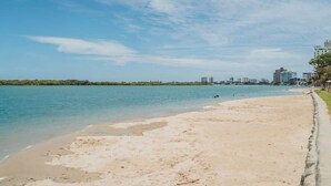 Une plage à l’eau claire, un rivage sablonneux et, au loin, le profil d’une ville.