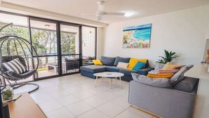 Un salon moderne avec un canapé, un fauteuil, une table basse et un tableau accroché au mur.