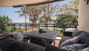 Relax in a shaded outdoor space with a sofa set and table, surrounded by trees and a body of water.