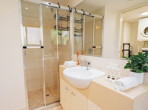 Bathroom features a glass-enclosed shower, sink, and mirror.