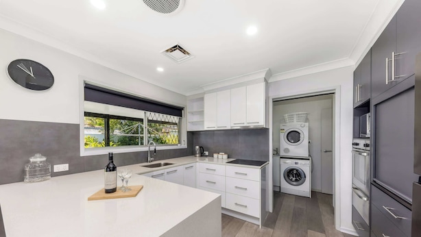 A modern kitchen with a central island, built-in appliances, and a large window. - Family Home in Maroochydore (Maroochydore Region)