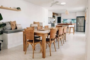 A modern kitchen with a dining area, featuring a wooden table and chairs, a ceiling fan, and a built-in island with a refrigerator.