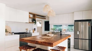A modern kitchen with a wooden island, stainless steel appliances, and a hanging light fixture. - Prime location with pool - walk to Coolum Beach (Coolum Region)
