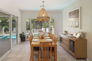 A dining area with a table set for four, a hanging light fixture, and a view of a swimming pool.