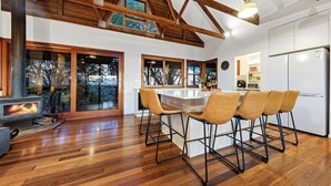 Una cocina moderna con una isla central, piso de madera y un amplio ventanal.