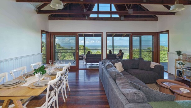 Una habitación amplia con comedor, un sofá grande y vistas al exterior.