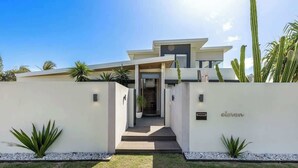 Une maison moderne avec une entrée centrale, une allée couverte et une pelouse bien entretenue.