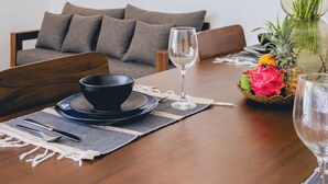 A dining area with a wooden table, a bowl, a wine glass, and a vase with flowers. - Santai Villa by Betterplace (Kerobokan)