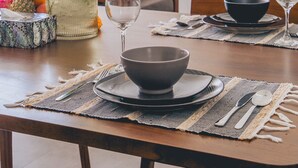 A dining table set with a vase of flowers, a wine glass, and a bowl. - Santai Villa by Betterplace (Kerobokan)