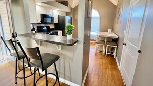 Una cocina moderna con una isla central, taburetes de bar y un área de comedor con mesa y sillas.