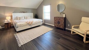 Un dormitorio con cama, ventilador de techo, mesita de noche, cómoda, silla, ventana y espejo.