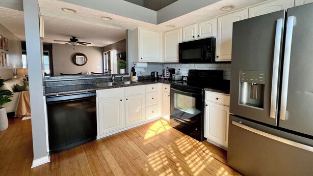 Una cocina moderna con armarios blancos, electrodomésticos de acero inoxidable y suelo de madera.