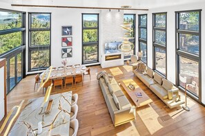 Un espacio habitable amplio con una chimenea grande, una mesa de comedor para seis personas y una zona de estar cómoda con un sofá y un sillón.