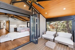 Ein modernes Interieur mit Holzboden, einer Glastür zum Balkon und einem weißen Sofa.