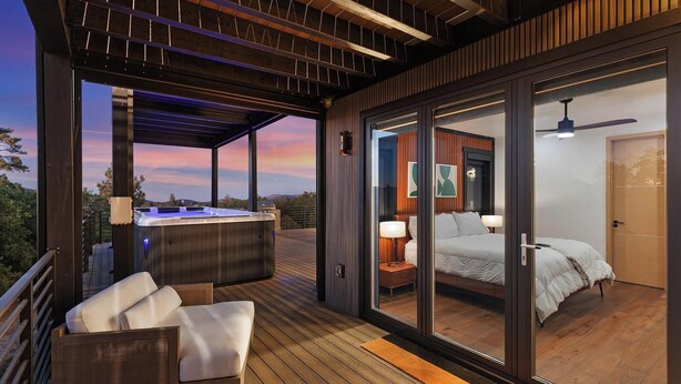 Una terraza moderna al aire libre con un jacuzzi, un sofá y un dormitorio con cama y mesita de noche.