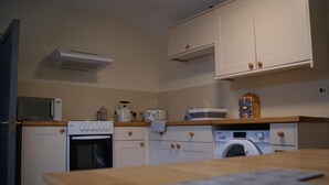 A compact kitchen with a microwave, toaster, oven, and washing machine. - Georgianstyle-2bed-smarttv-freeparking (Boston)