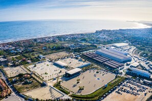 Vue aérienne d’une zone côtière comprenant un grand parking, un stade et des bâtiments industriels.